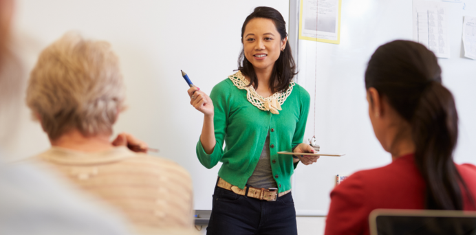woman teaching with the backs of two students visible